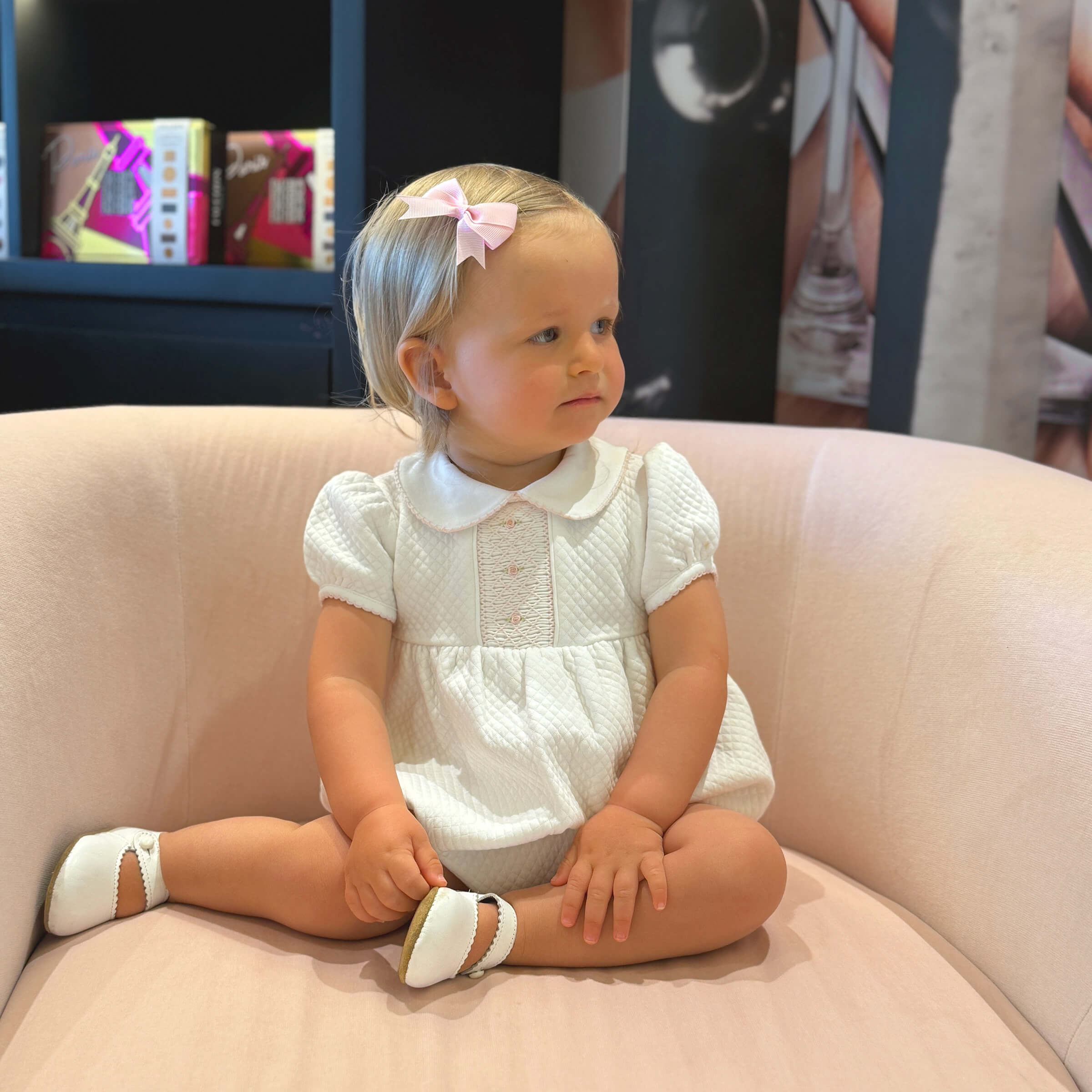 Baby wearing hand-smocked white bubble romper from Cheris Blanc Couture.