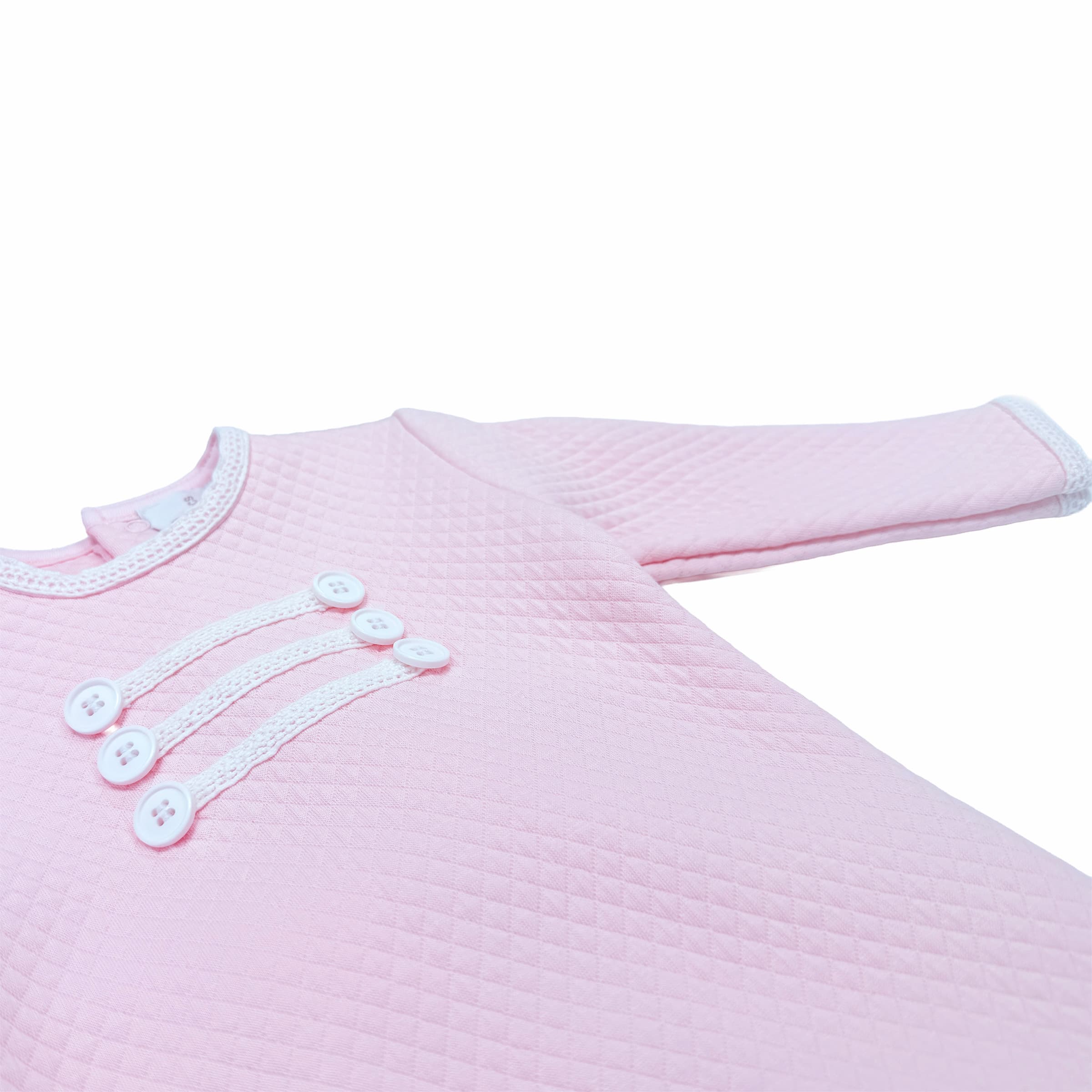 Close-up of lace trim and decorative button detail on baby girl babygrow