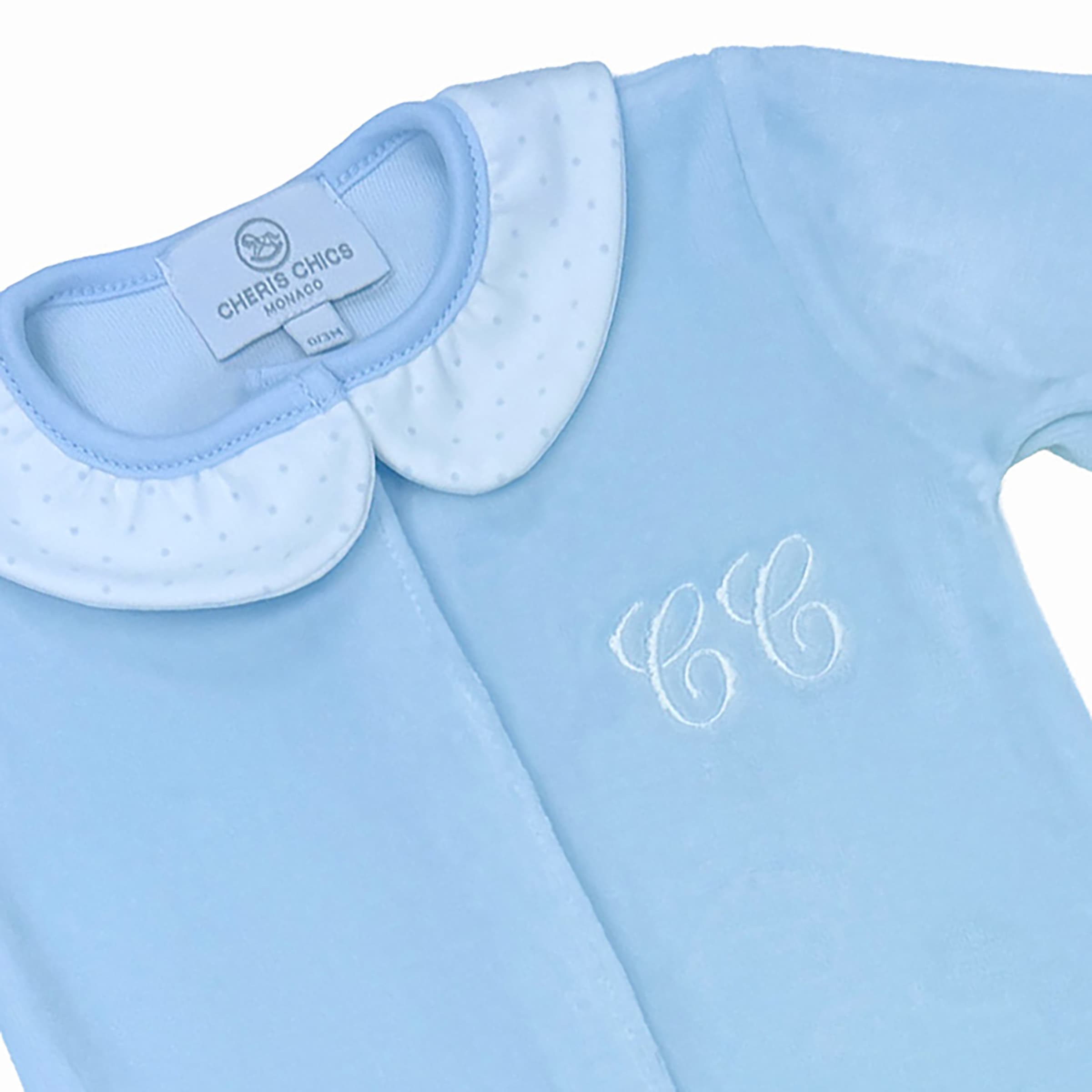 Close-up of chest embroidery on luxury saphir blue velour baby sleepsuit.