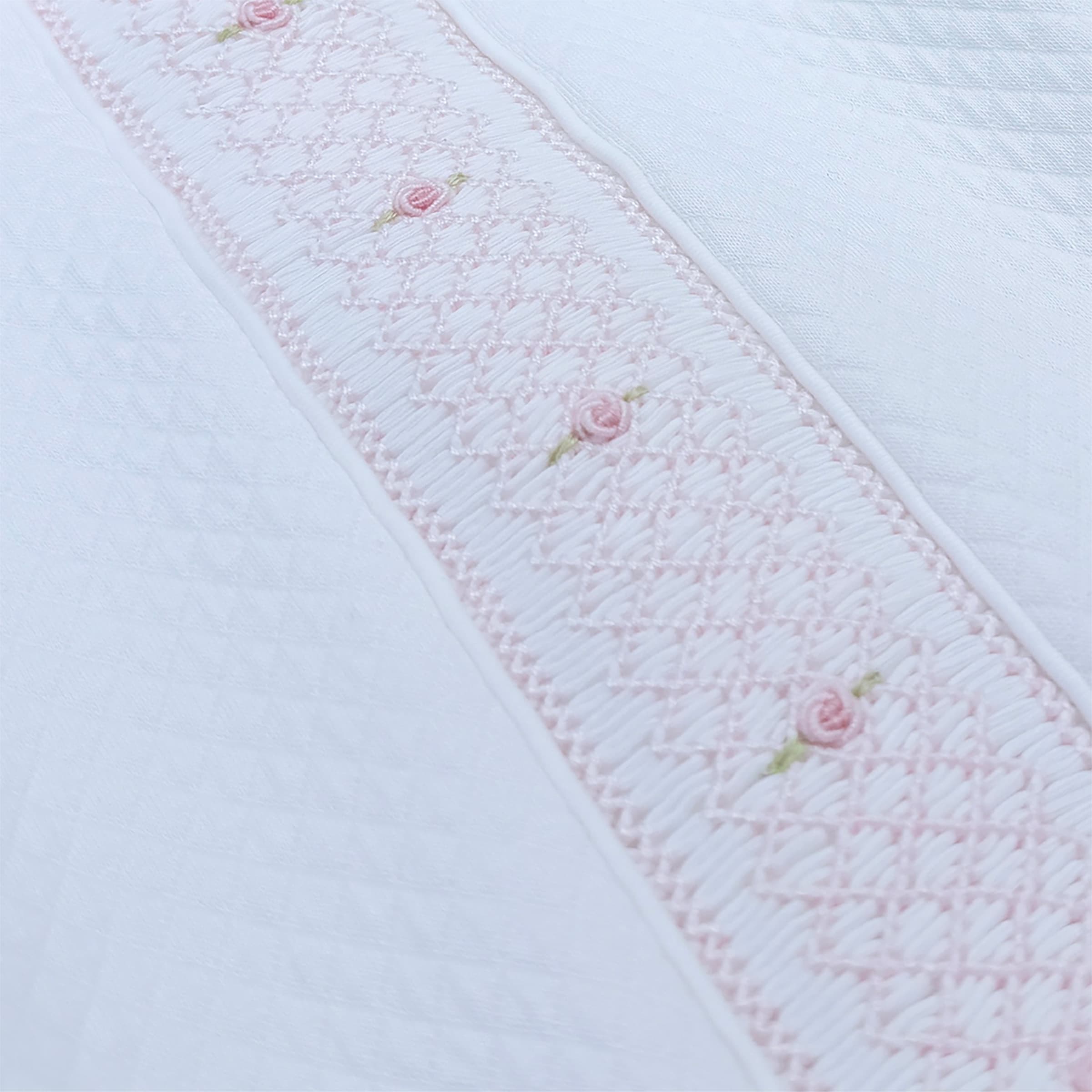 Close-up of artisanal hand-gauged smocking and rosette detailing on the Couture Mademoiselle Babygrow.