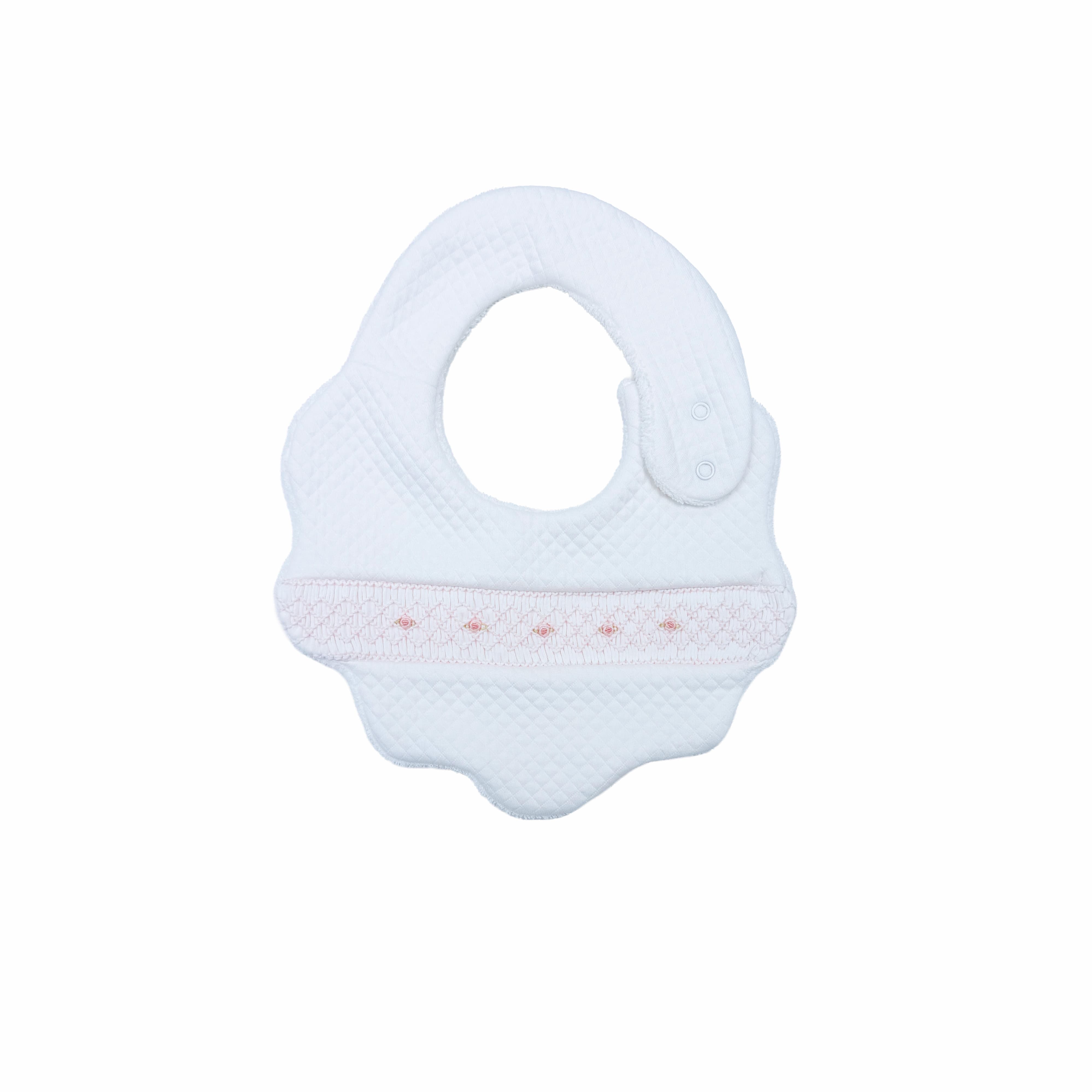 Front view of white quilted baby bib with hand-smocked rosette detailing.