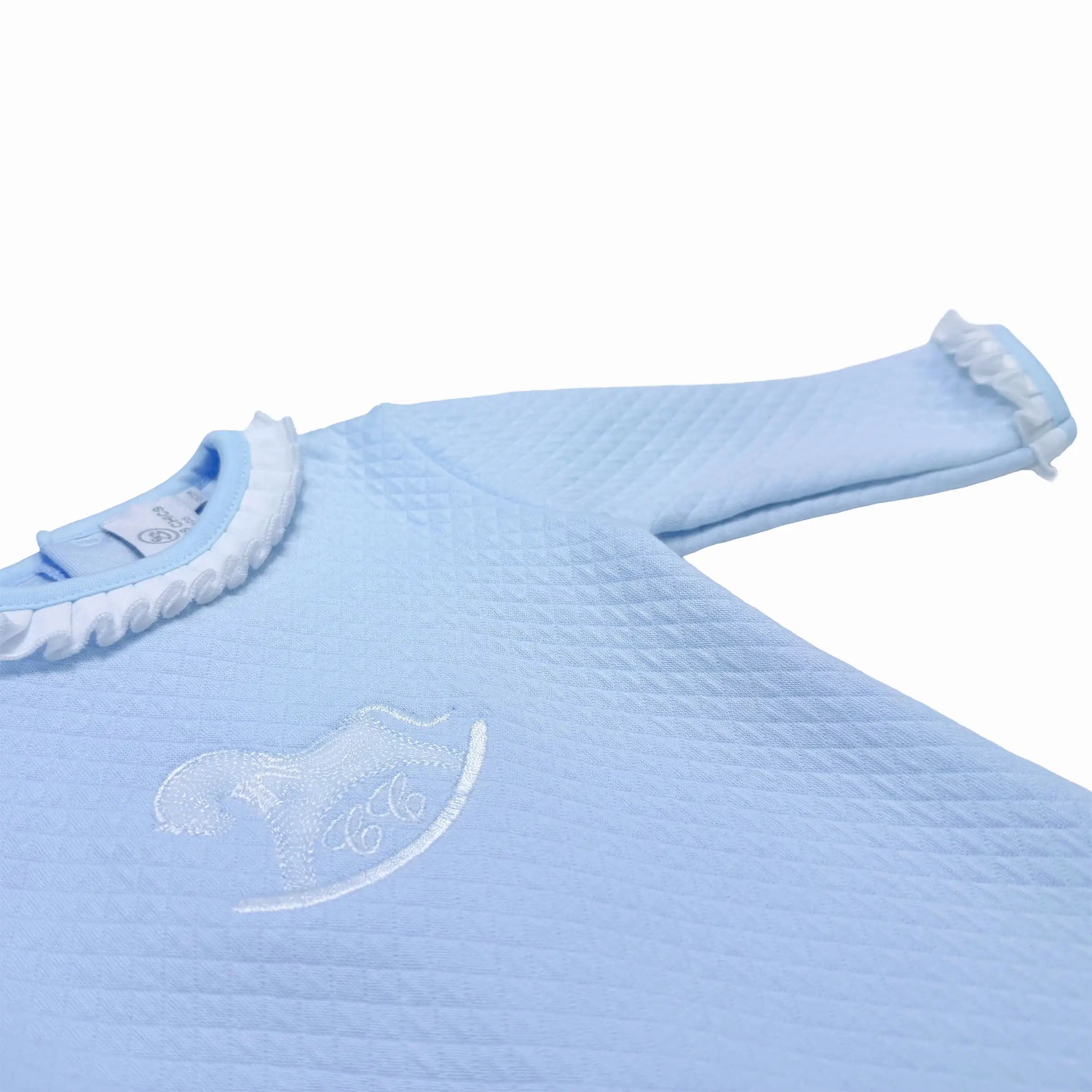 Close-up of embroidered chest motif and volant frill trimming on baby boy babygrow