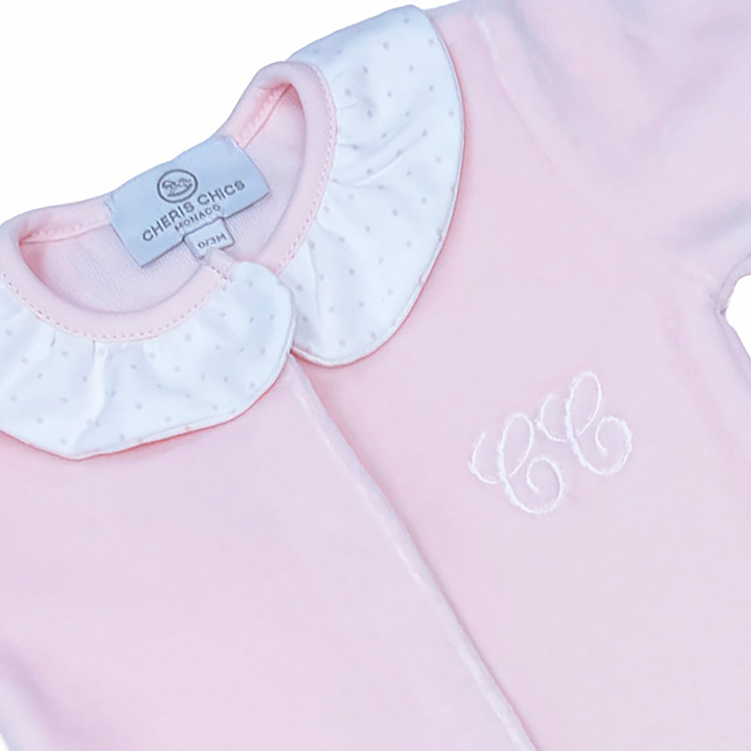 Close-up of delicate chest embroidery on rose velour baby sleepsuit.